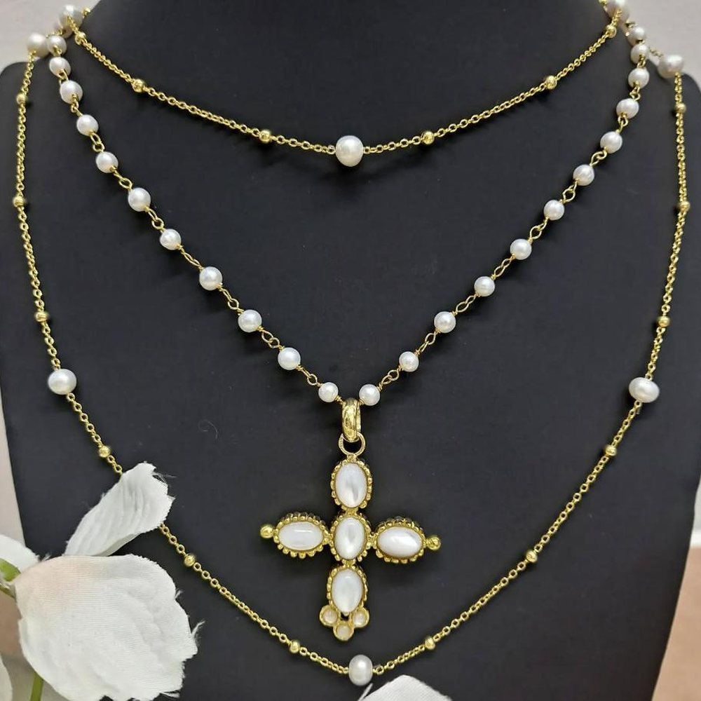 Colares em ouro com pérolas e um pendente em forma de cruz com pérolas, sobre expositor escuro